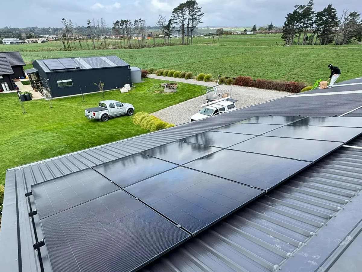 A 10.01kW EFS Solar array on a charcoal metal roof at a rural Brixton property, Taranaki, green paddocks behind